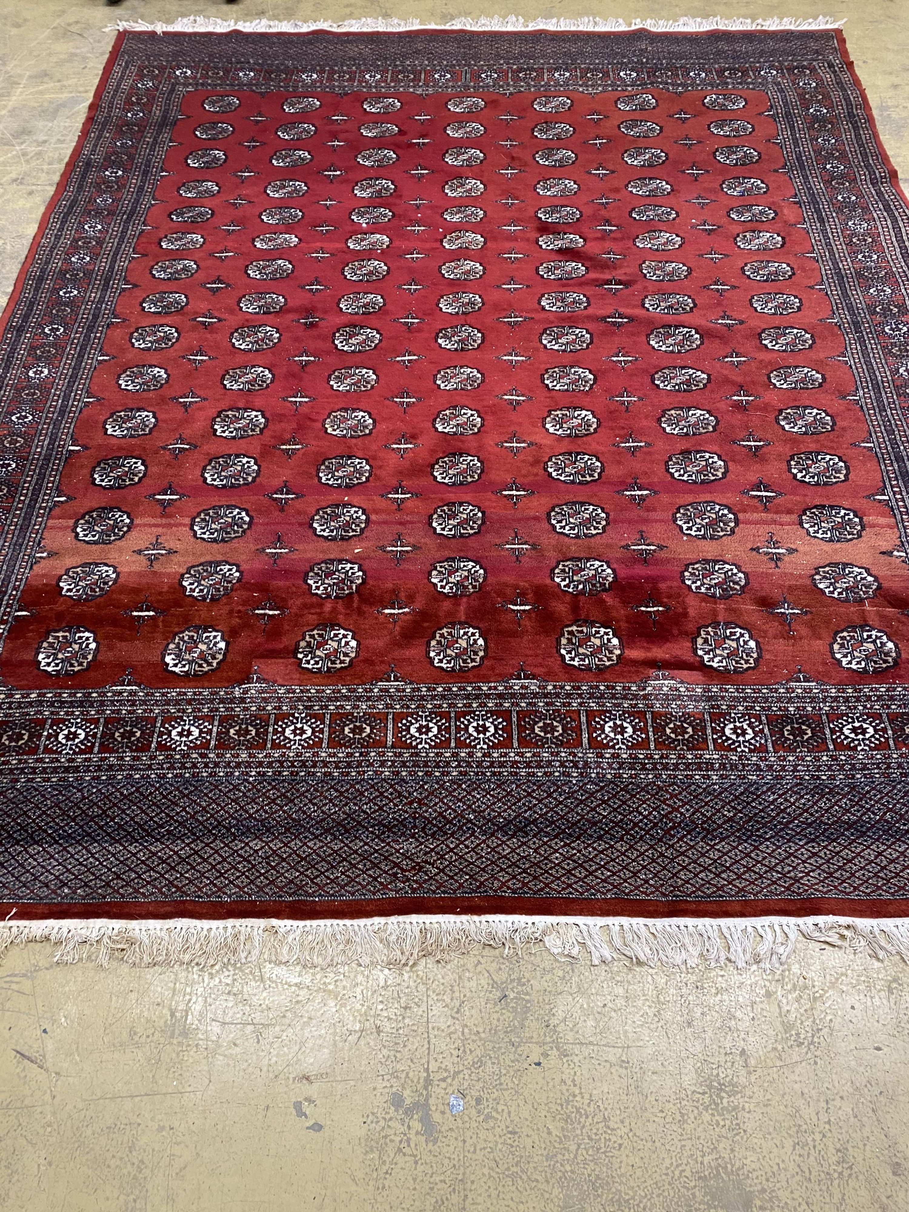 A Bokhara burgundy ground carpet, 334 x 274cm